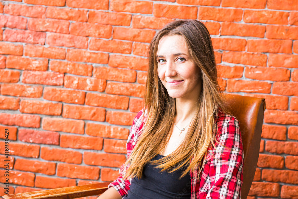 beautiful smart woman sits on chair near brick wall beautiful smart woman sits on chair near brick wall