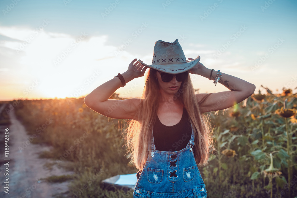 Girl in a cowboy hat in a sunflower field. Sunset