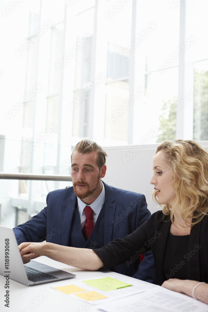 Two Businesspeople Using Laptop At Desk In Modern Office Two Businesspeople Using Laptop At Desk In Modern Office