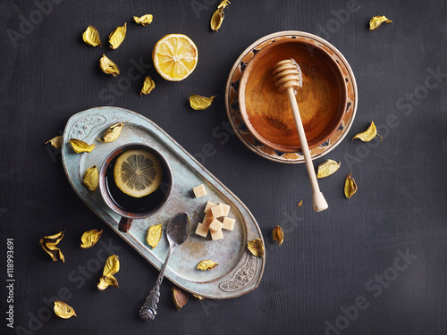 Hot black tea in vintage metal cup served with lemon, bronw sugar and figs. Copy space.