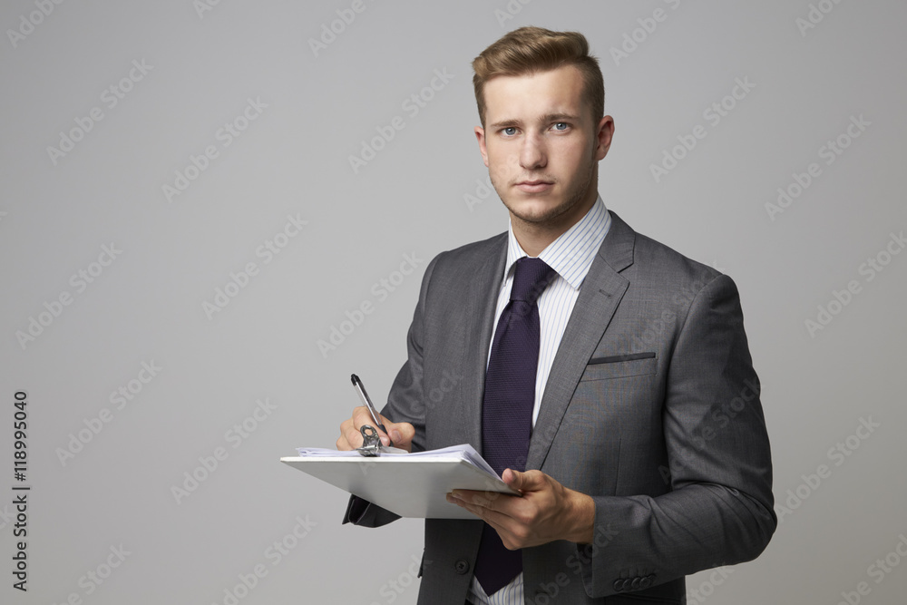 Studio Portrait Of Businessman Writing On Clipboard Studio Portrait Of Businessman Writing On Clipboard