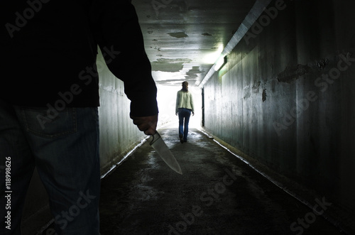 Man carries a knife follows a young woman in a dark tunnel