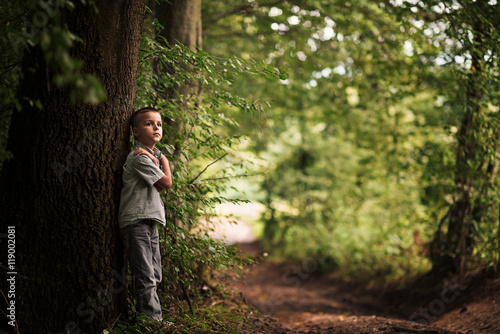 boy standing under a tree 