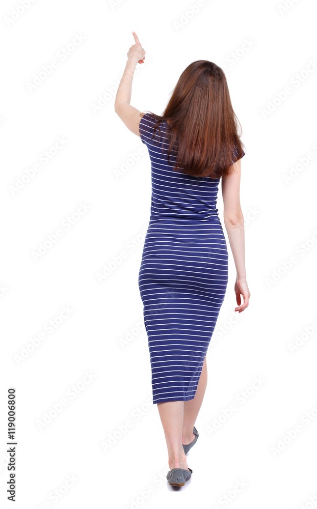 back view of pointing walking woman. going girl pointing. backside view of person. brunette in a blue striped dress went off showing thumb up. back view of pointing walking woman. going girl pointing. backside view of person. brunette in a blue striped dress went off showing thumb up.