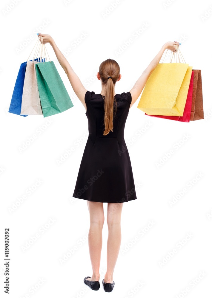 back view of woman with shopping bags. Isolated over white background. Blonde in a short black dress holding aloft shopping bags. back view of woman with shopping bags. Isolated over white background. Blonde in a short black dress holding aloft shopping bags.