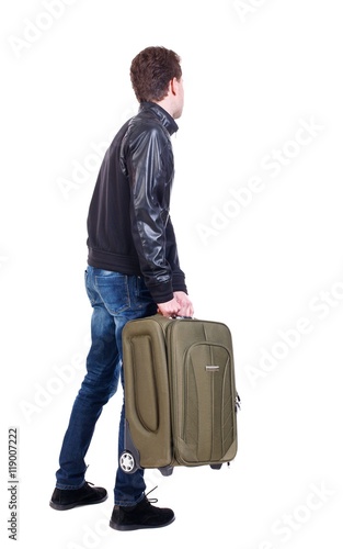 Back view of man with green suitcase looking up. traveler is carrying a suitcase ready to travel.