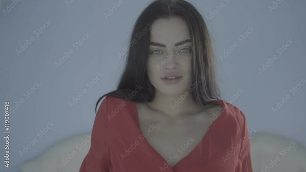 Closeup portrait of beautiful young sexy brunette woman wearing red dress smiling in her bedroom Closeup portrait of beautiful young sexy brunette woman wearing red dress smiling in her bedroom