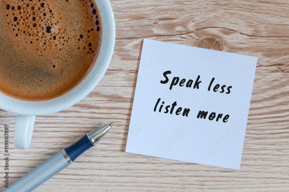 Speak Less Listen More phrase written on paper and cup of brasilian coffee at wooden background
