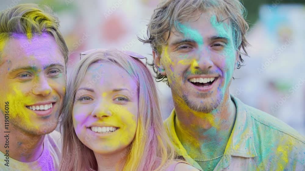 Excited faces of beautiful young people covered in colors smiling at camera Excited faces of beautiful young people covered in colors smiling at camera