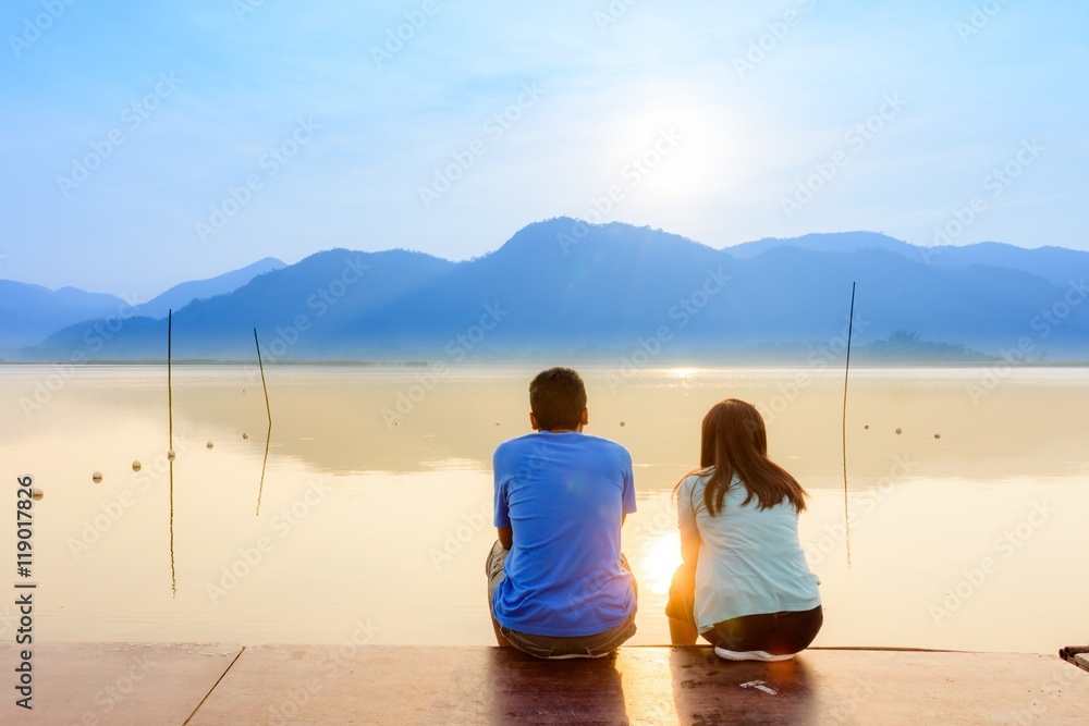 A couple on the wooden port at a lake on sunset
