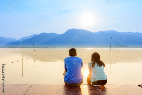 A couple on the wooden port at a lake on sunset