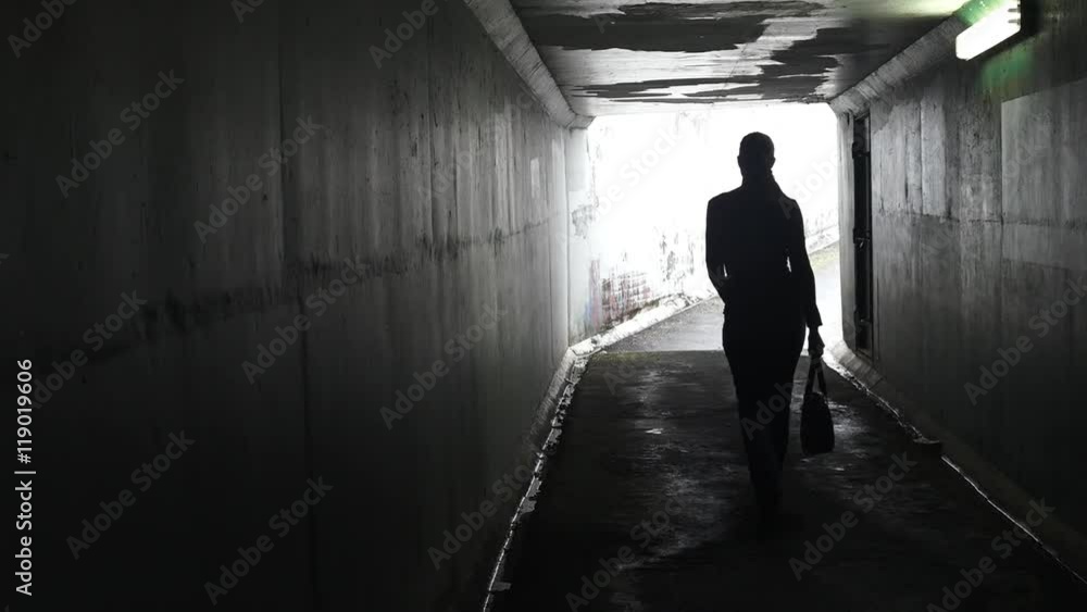 Silhouette of a man thief ambush steals a bag from a woman in a dark tunnel. Violence against women concept. Real people, copy space Silhouette of a man thief ambush steals a bag from a woman in a dark tunnel. Violence against women concept. Real people, copy space