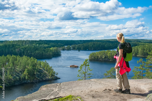 Woman hiking and looking at view on high cliff in National Park in Finland