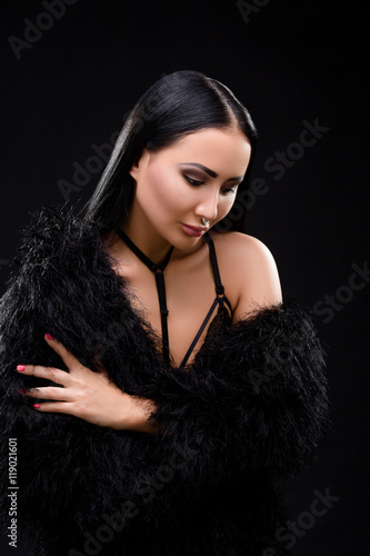 Beautiful brunette in black dress with perfect decollete over black background. Elegant and gorgeous vampire in studio.