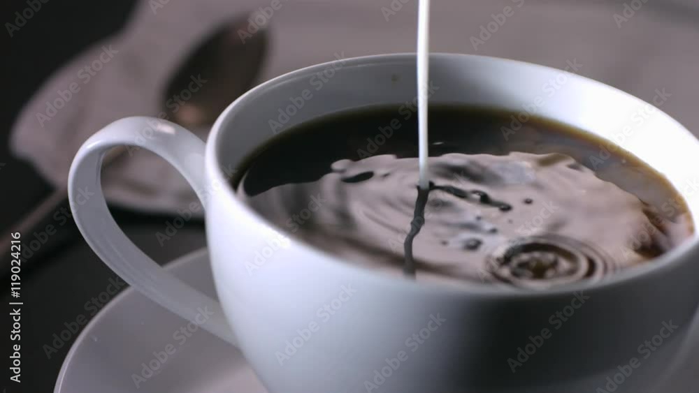 Slow motion shot of milk being poured into coffee cup Slow motion shot of milk being poured into coffee cup