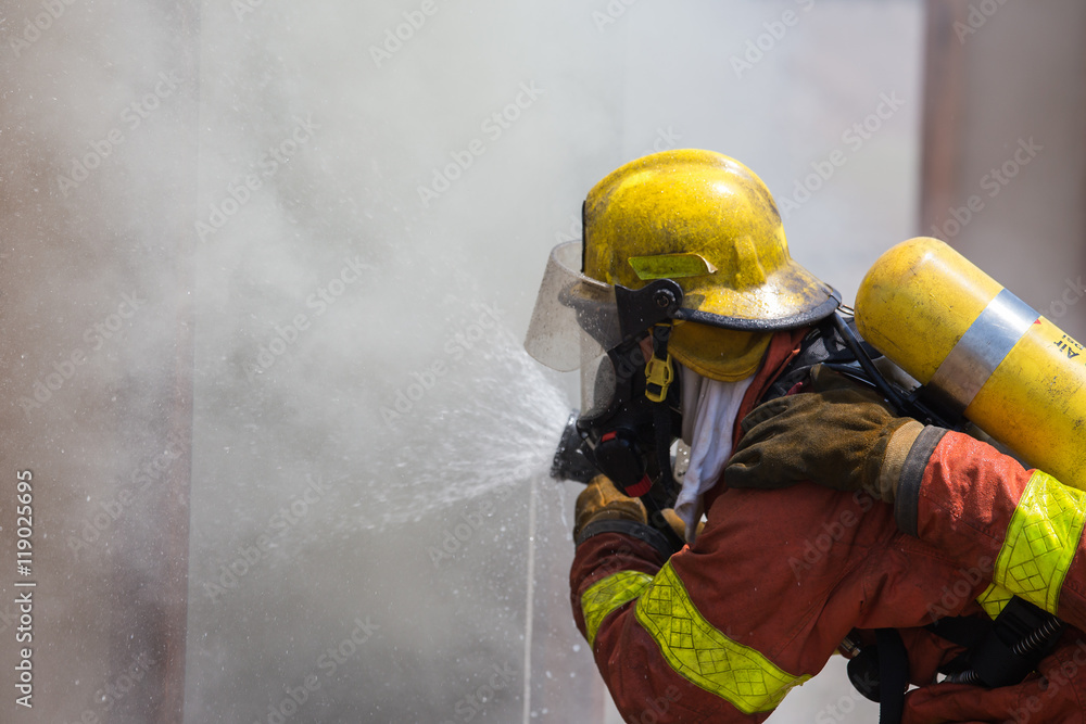 Fototapeta premium firefighter in fire protection suit spraying water to fire 