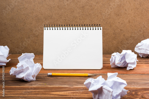 Searching an idea, motivation, result, dwaing scetches. White blank notepad book at office worplace crampled paper notes on wooden grunge background. Copy space for ad text. photo