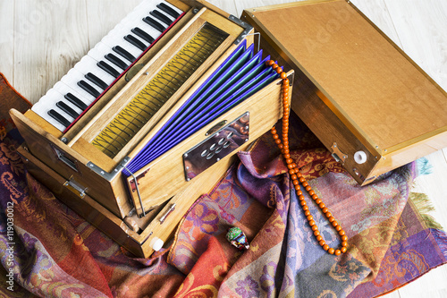 Indian harmonium, a traditional wooden keyboard instrument, close-up.  Bright colorful musical instrument on the patterned wrap photo