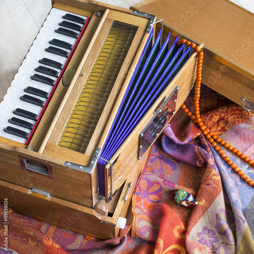 Indian harmonium, a traditional wooden keyboard instrument, close-up.  Bright colorful musical instrument on the patterned wrap
