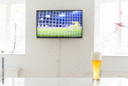 Elfmeter beim Fußball als Fernsehbild und ein Weißbier auf einem Tisch