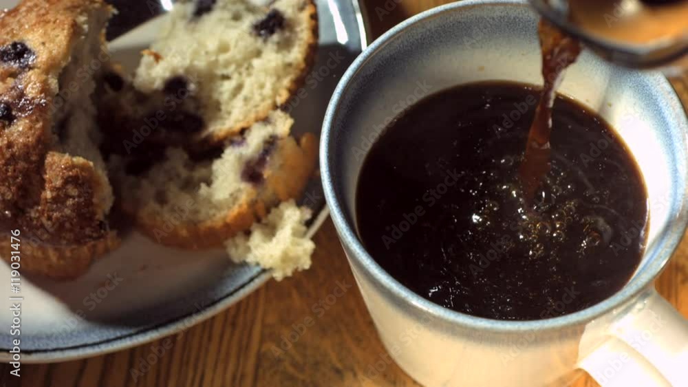 Slow motion overhead shot of coffee and muffin on breakfast table Slow motion overhead shot of coffee and muffin on breakfast table