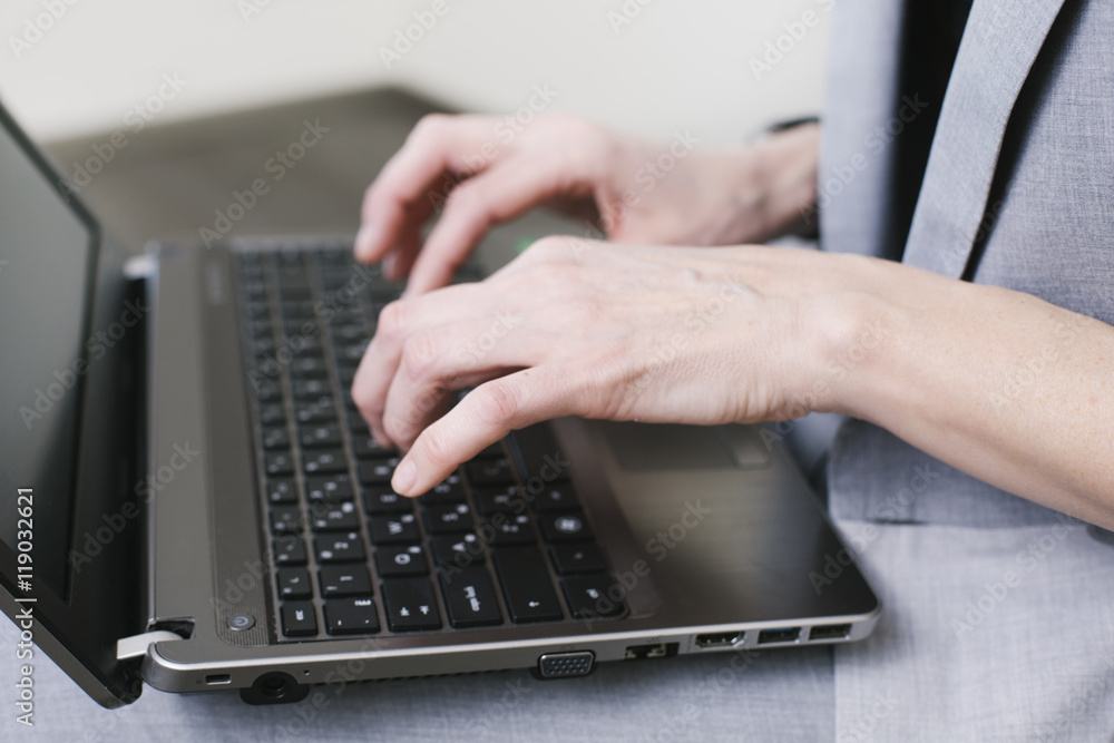 Business woman typing on the laptop on the knees with pencil in her hand in the office. Close-up hands Business woman typing on the laptop on the knees with pencil in her hand in the office. Close-up hands