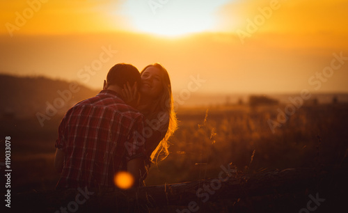 Boy kisses woman's neck while she looks up in the golden sky