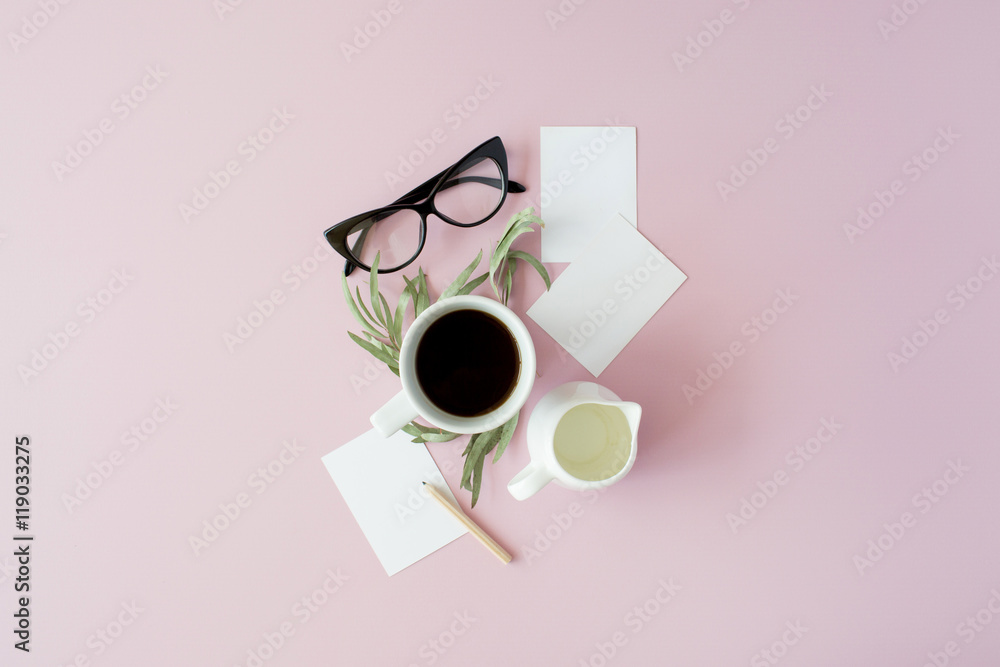 Cup of coffee, paper notes, pencil, green leaves and glasses on pink background. Flat lay, top view