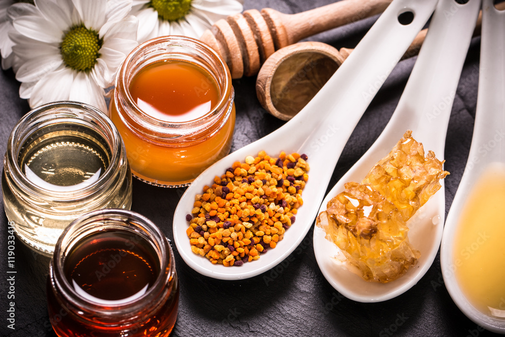 Honey in jar with honey dipper on black stone background Honey in jar with honey dipper on black stone background
