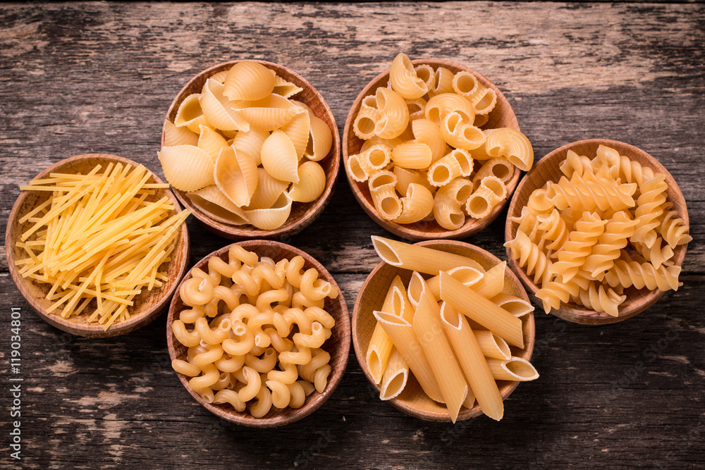 Various mix of pasta on wooden rustic background. Diet and food