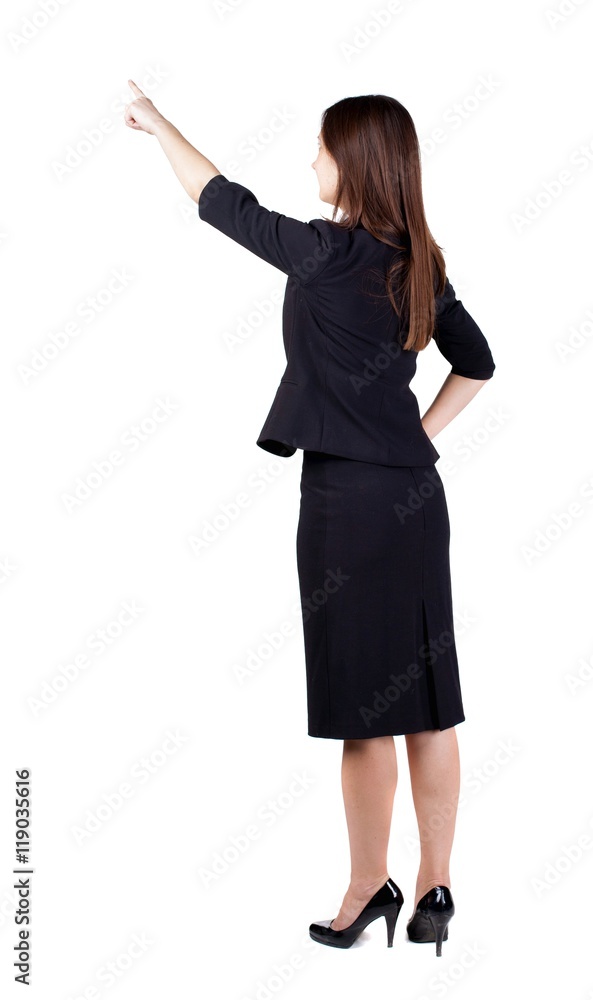 Back view of young brunette business woman pointing at wall. beautiful girl in dark suit. Rear view people collection. backside view of person. Isolated over white background. Back view of young brunette business woman pointing at wall. beautiful girl in dark suit. Rear view people collection. backside view of person. Isolated over white background.