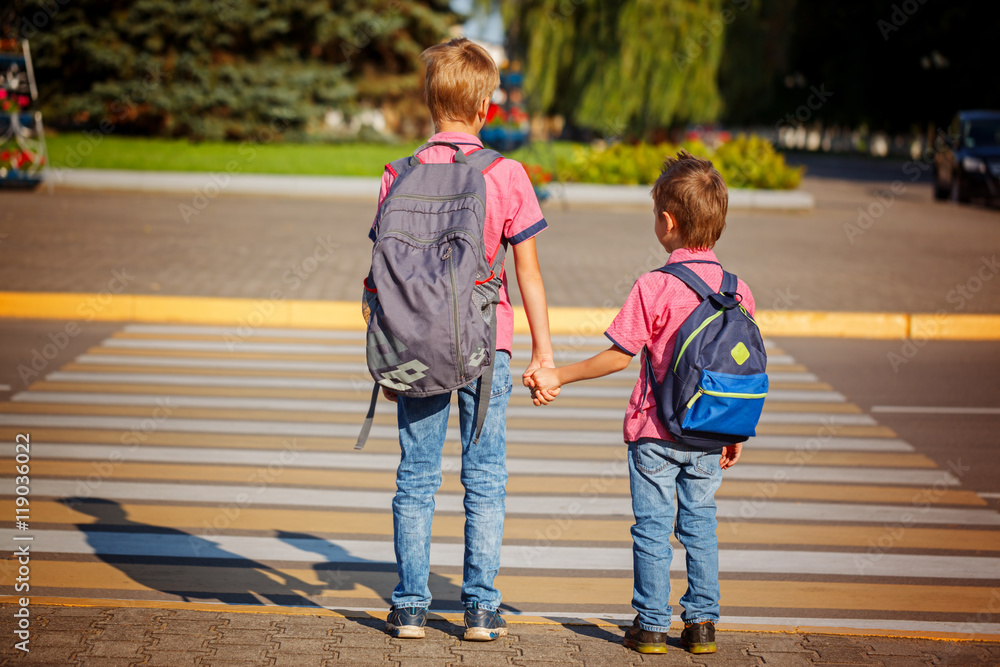 Two brothers with backpack walking, holding on warm day on the Two brothers with backpack walking, holding on warm day on the
