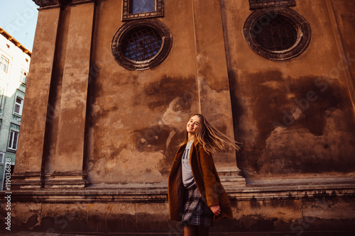 Marvelous young woman in autumn clothes whirls before old cathed photo