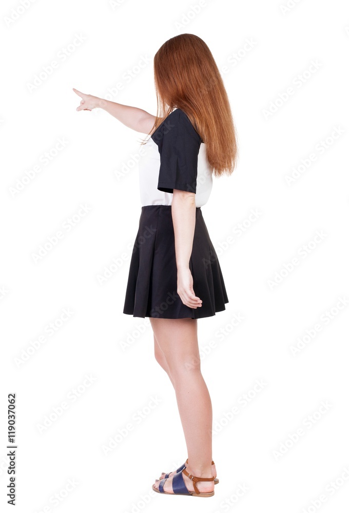 Back view of young redhead woman pointing at wall. beautiful girl in dress. Rear view people collection. backside view of person. Isolated over white background. Back view of young redhead woman pointing at wall. beautiful girl in dress. Rear view people collection. backside view of person. Isolated over white background.