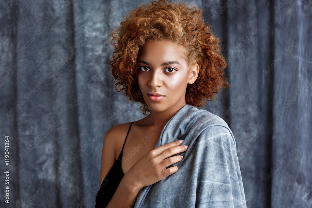 Fototapeta premium Young beautiful african girl posing, wrapping up in grey cloth.