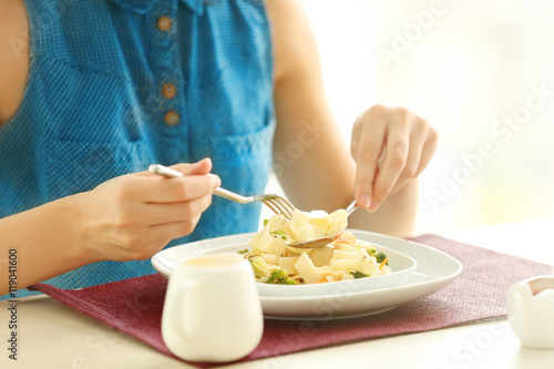 Woman eating delicious pasta in restaurant