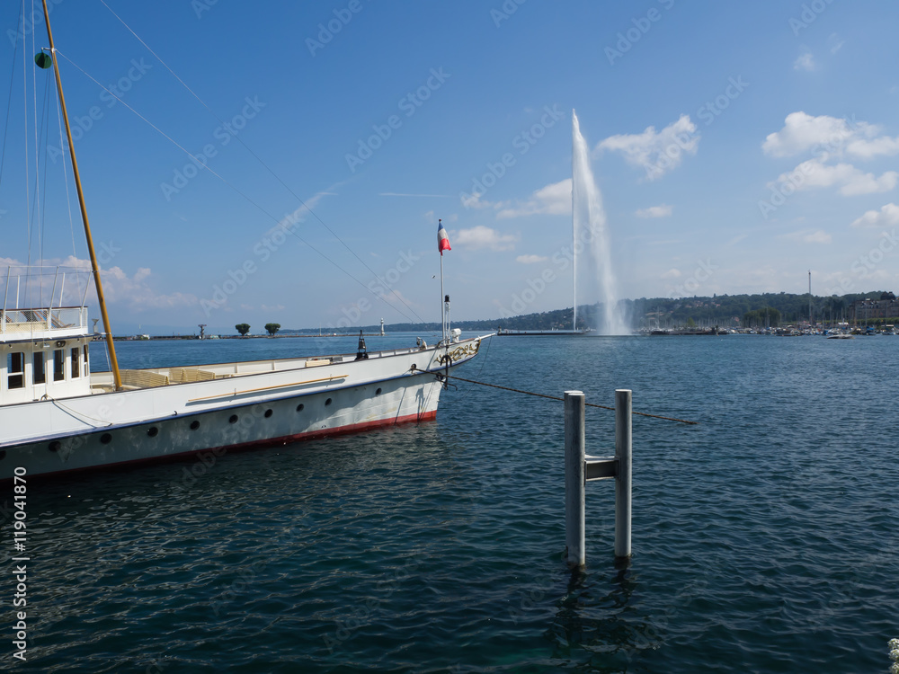 Fototapeta premium Paisaje acuático con un barco blanco sobre el agua azul y vistas al Jet d'Eau en Ginebra , Suiza verano de 2016