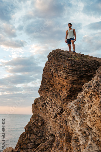 Young sportsman standing on the mountain rock by the sea