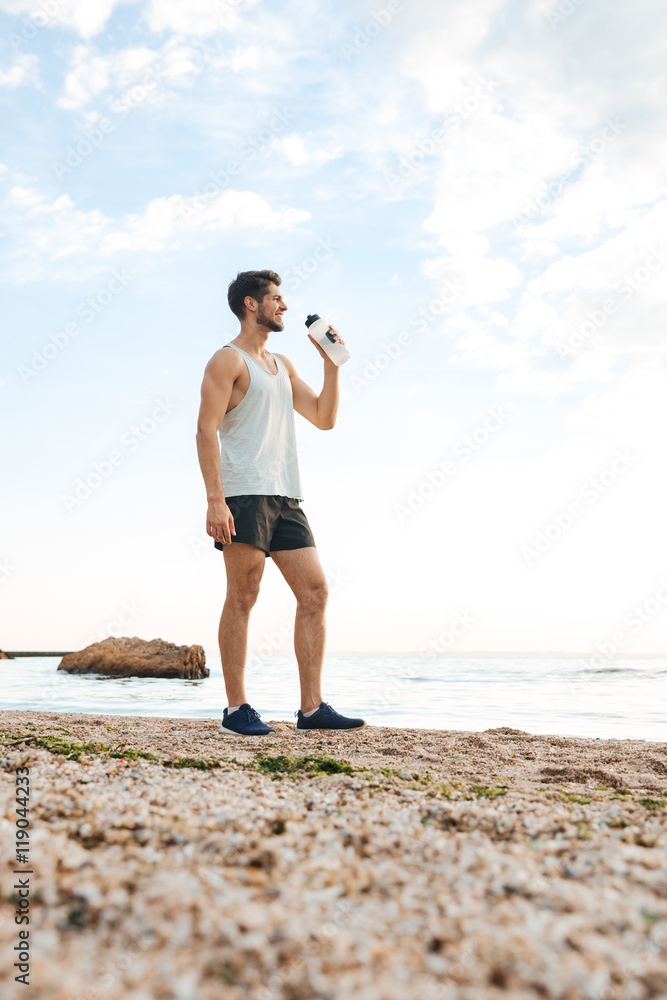 Young sporty man athlete resting after jogging and drinking water