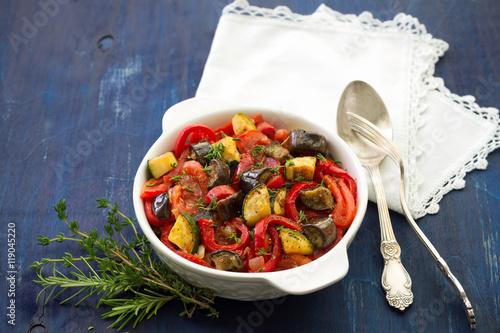 Ratatouille, a traditional French dish of vegetables in a white ceramic bowl on a dark blue background photo