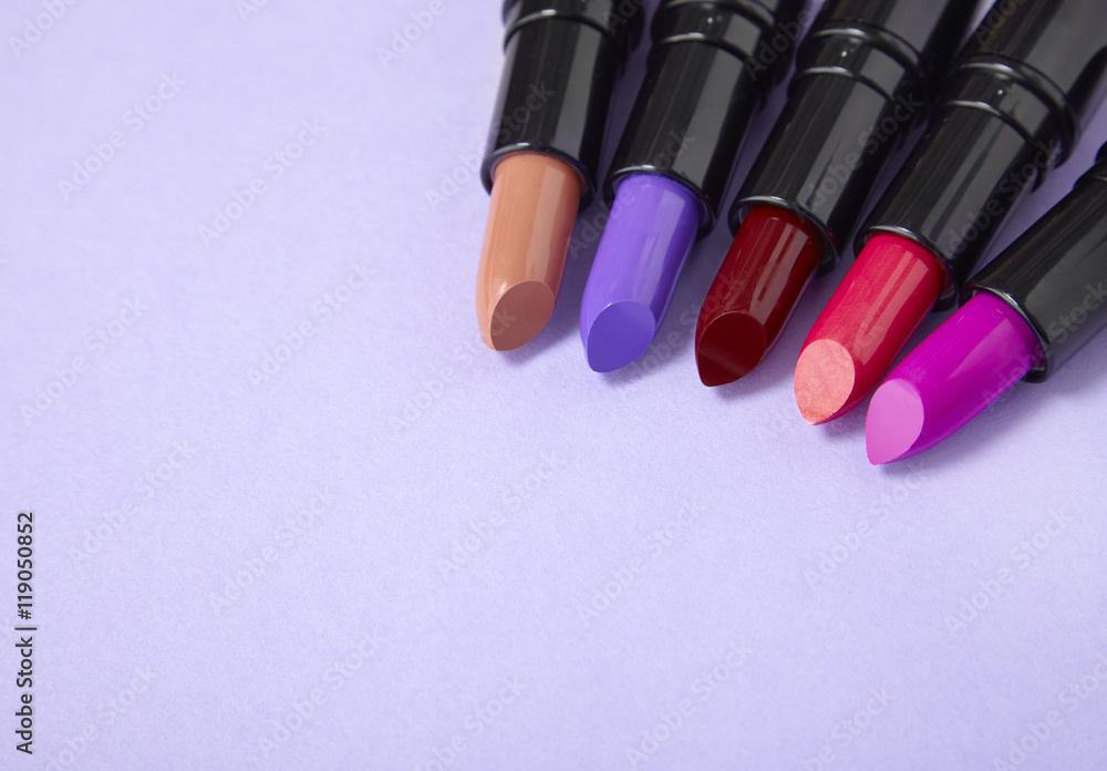 Lip stick makeup arranged on a pale purple background forming a page border Lip stick makeup arranged on a pale purple background forming a page border