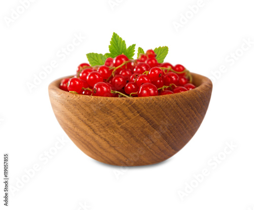 Redcurrant in a wooden bowl. Ripe and tasty currant isolated on white background. Red berries with leaves.