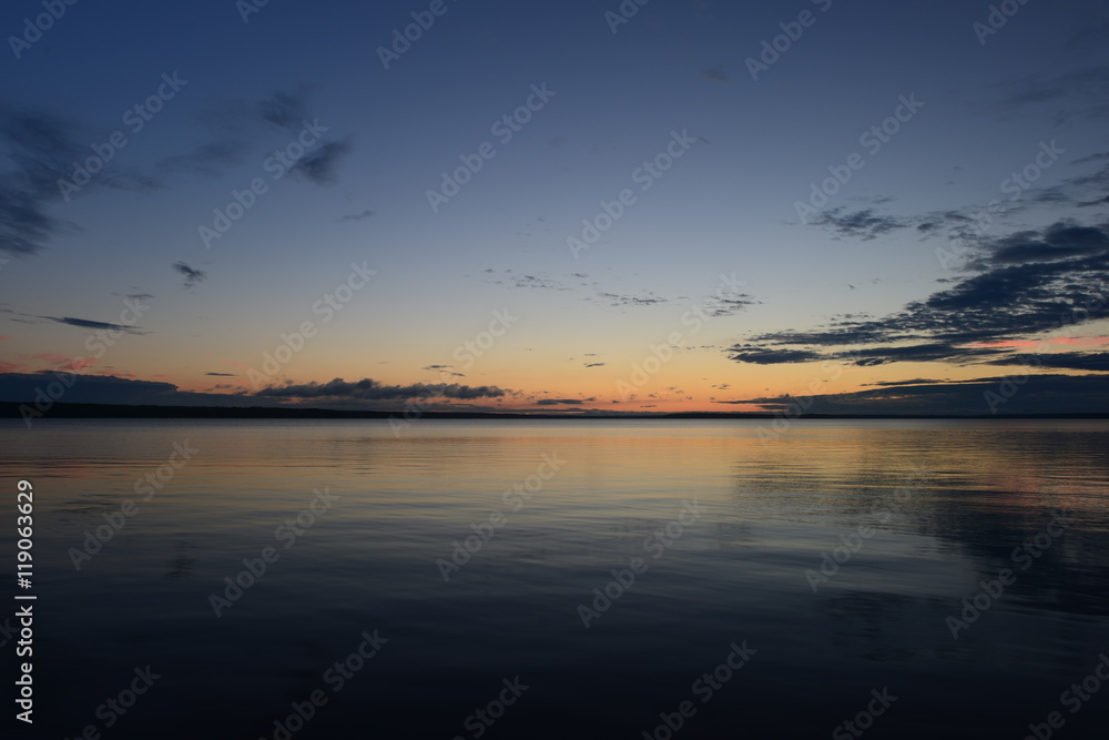 Weather afterglow of summer sunset on lake water surface
