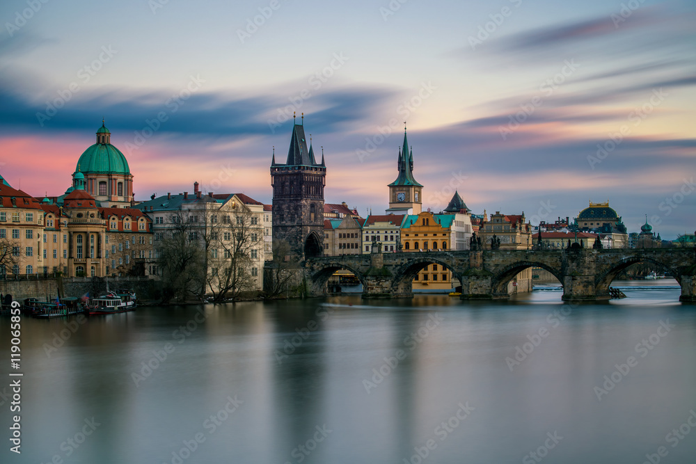 Amazing towers of Charles bridge and old town district with reflection at Vltava river during cloudy sunset, Prague, Czech republic