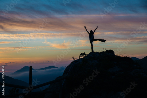 Tourist with arms up at dusk in mountains photo