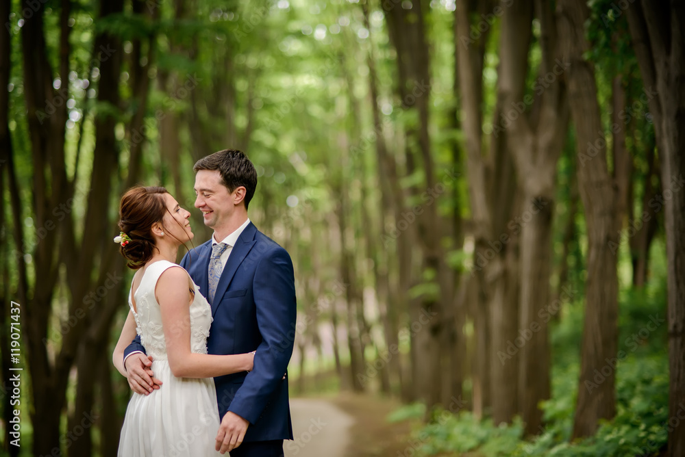 Bride and Groom at wedding Day walking Outdoors on spring nature. Bridal couple, Happy Newlywed woman and man embracing in green park. Loving wedding couple outdoor.