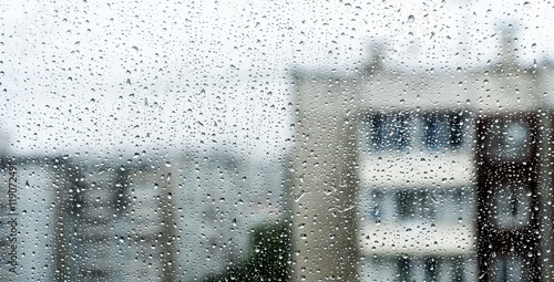 rain drop on window glass with blur houses in background