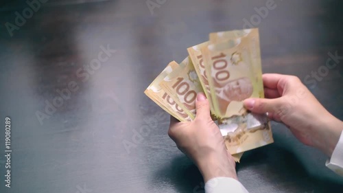 View of a woman Counting Many Canadian 100 bills, polymer plastic type, Woman not happy about not having enough money