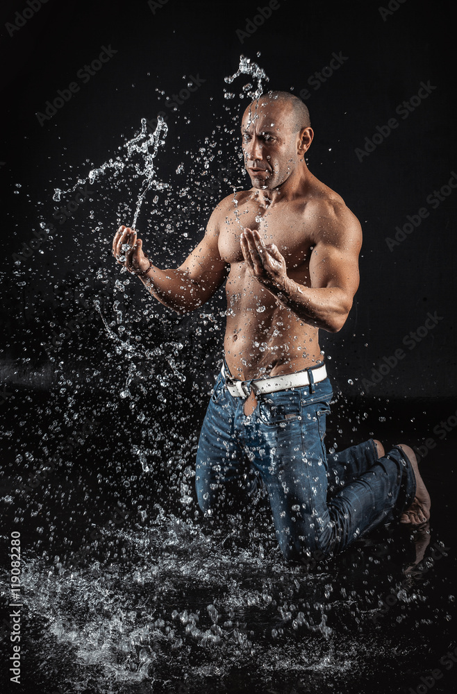 Fototapeta premium very muscular handsome athletic man striking with a hand on wate