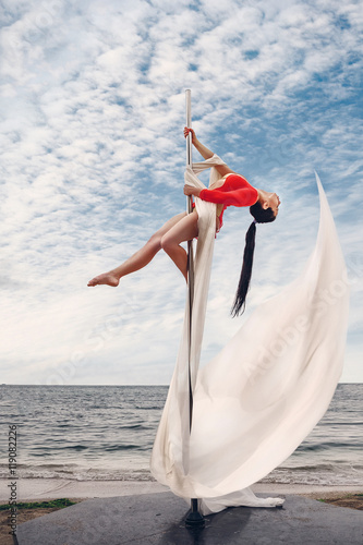 Female pole dancer against the sea and sky